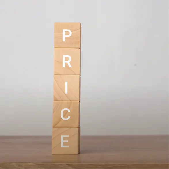 Holzklötze sind gestapelt und bilden das Wort PRICE auf einer glatten Tischoberfläche vor hellem Hintergrund